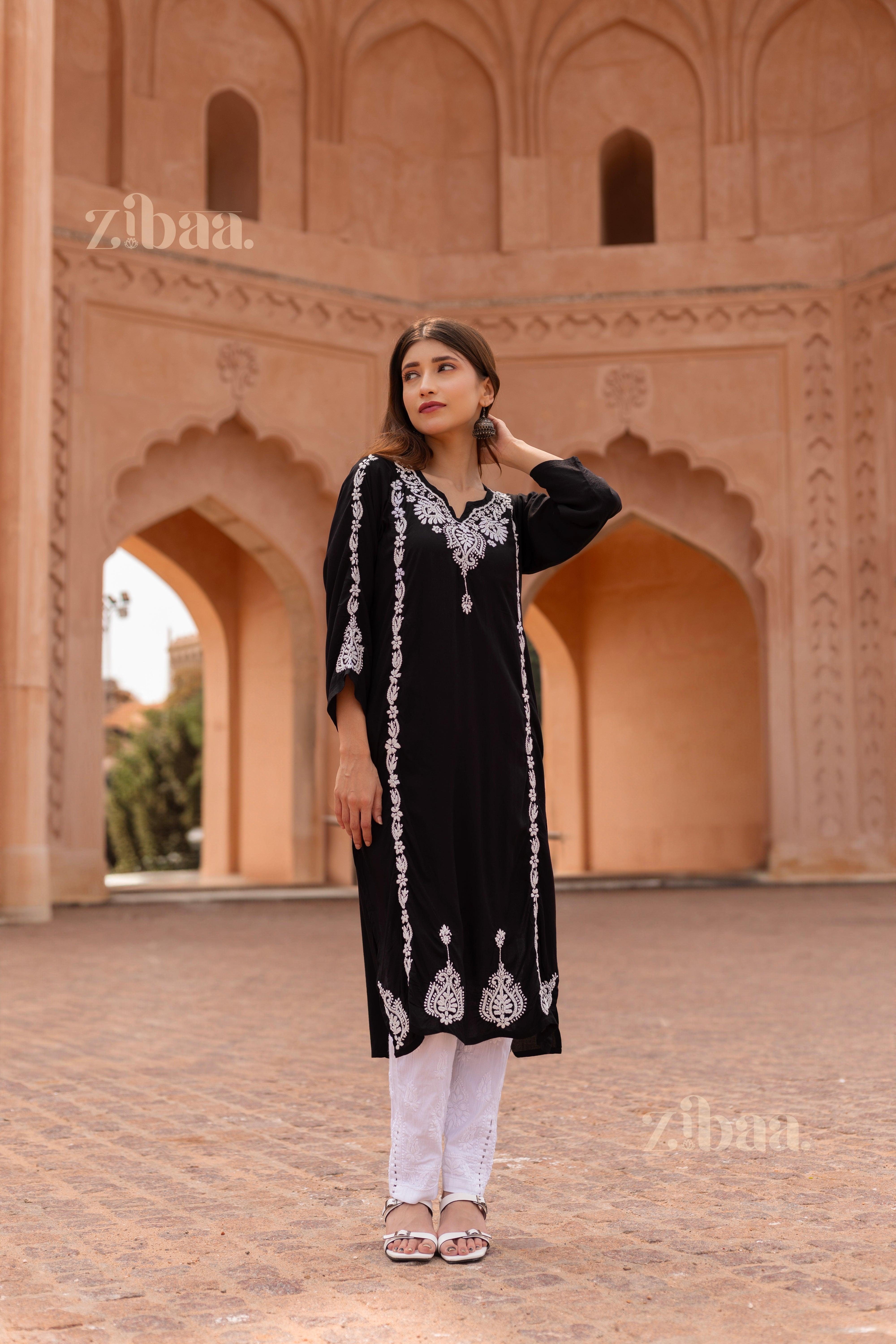 Model wearing a Black Chikankari Kurti with intricate white embroidery, posing in front of a stunning heritage architectural backdrop