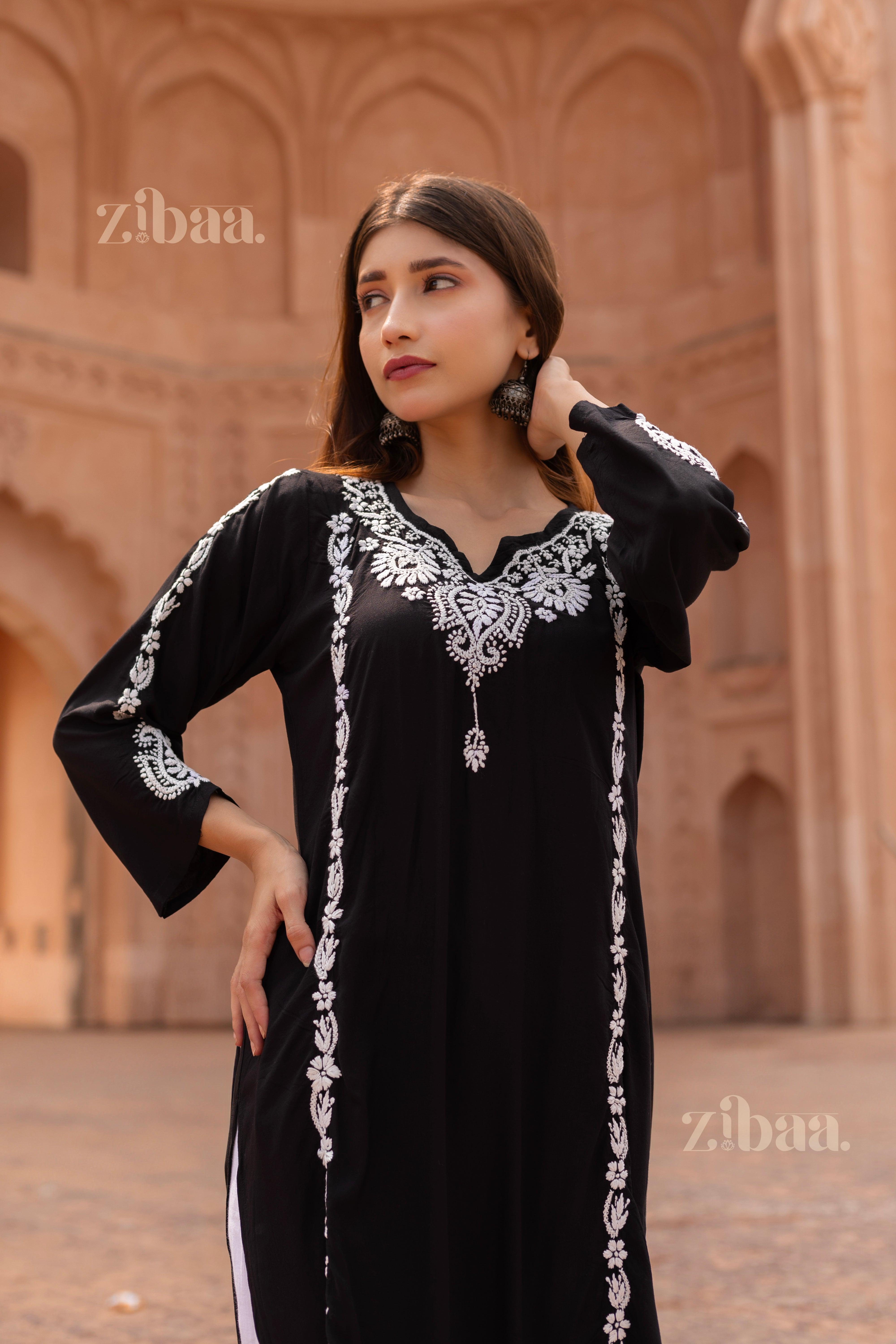 Model in a Black Chikankari Kurti with detailed white embroidery, striking a graceful pose against the backdrop of a heritage monument.