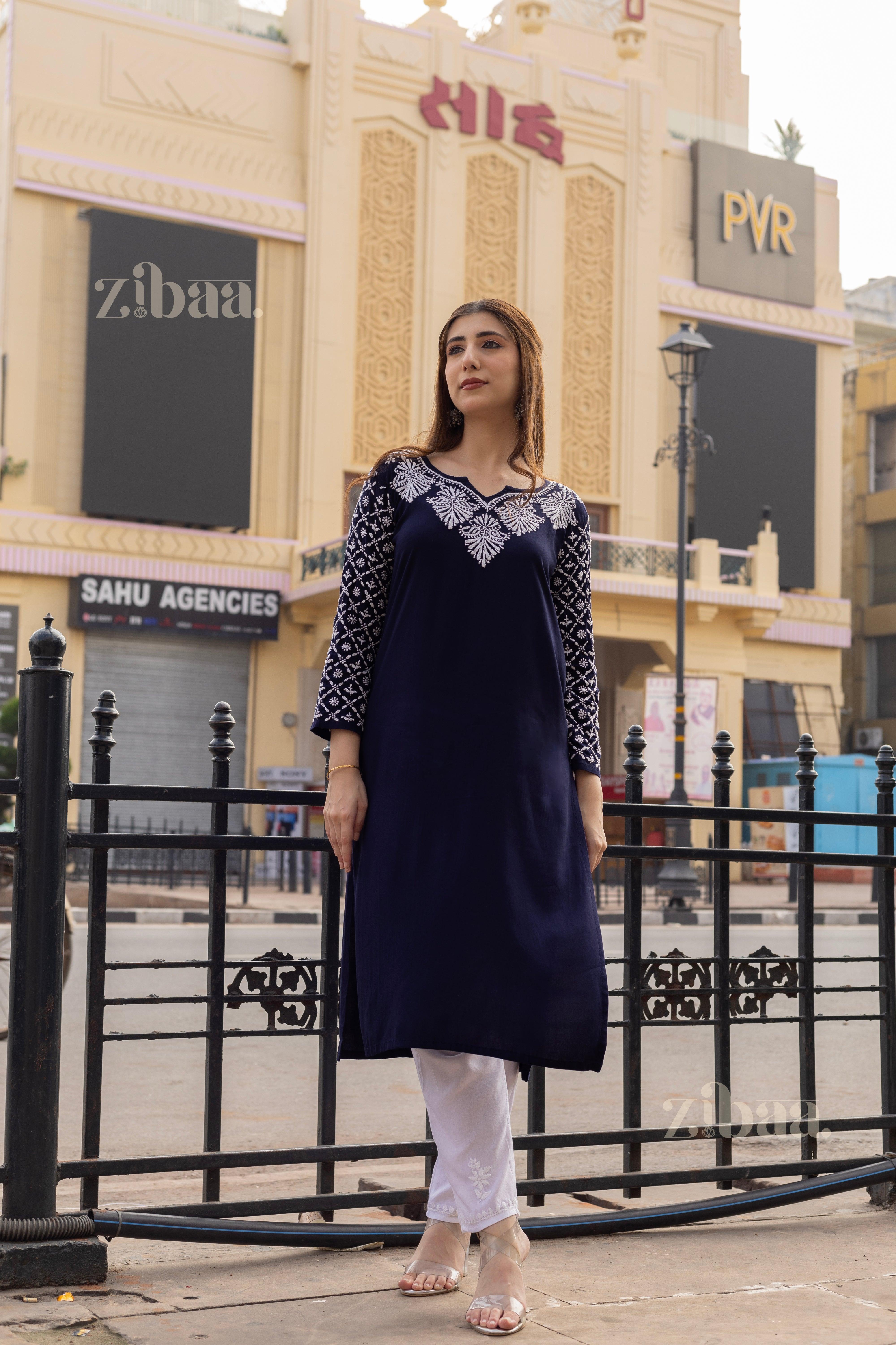 Model wearing a Blue Chikankari Kurti with white embroidery, paired with white pants, posing elegantly in an urban outdoor setting.