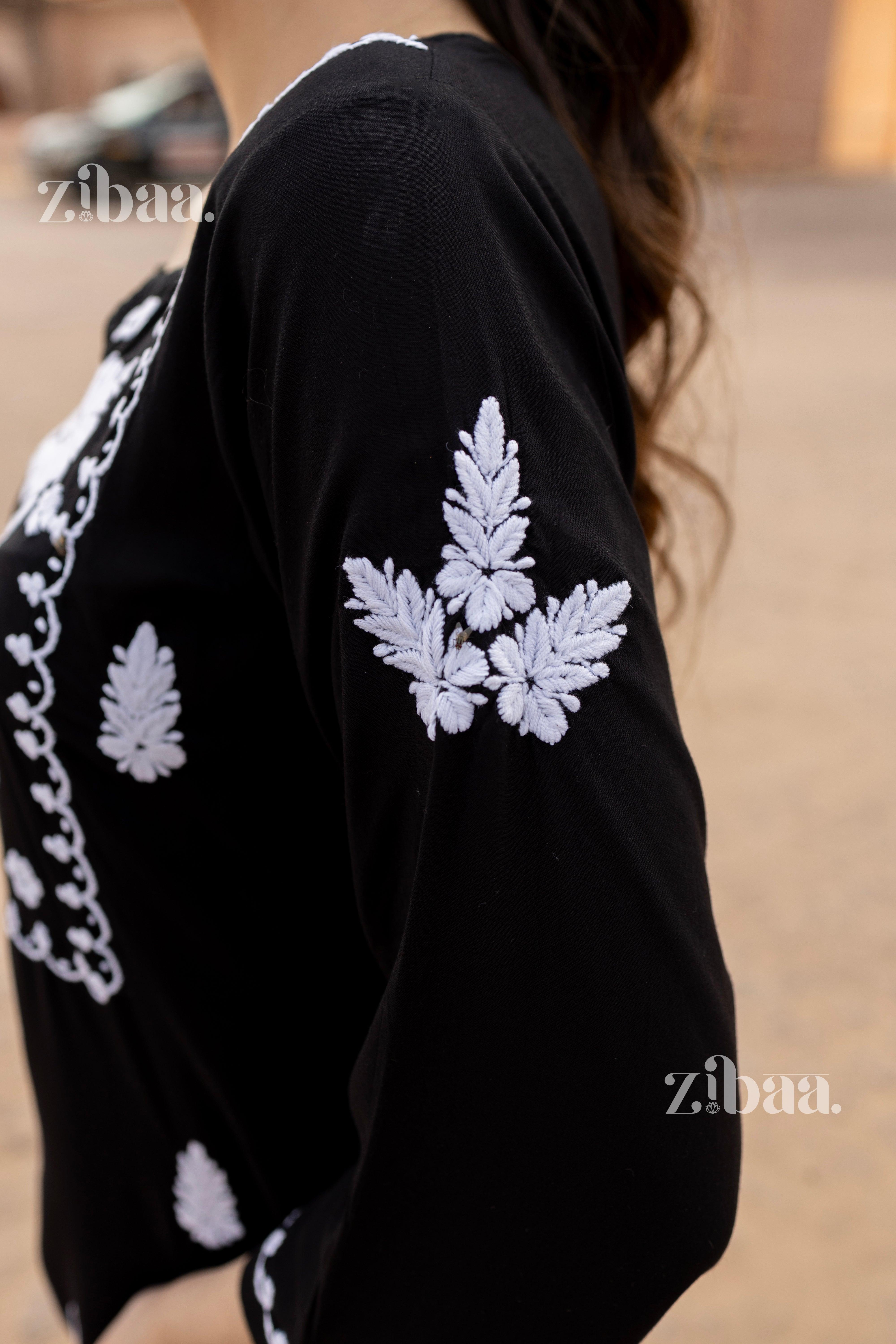 Close-up of the sleeve of a black Chikankari kurti, showing detailed white floral embroidery, highlighting its intricate craftsmanship.