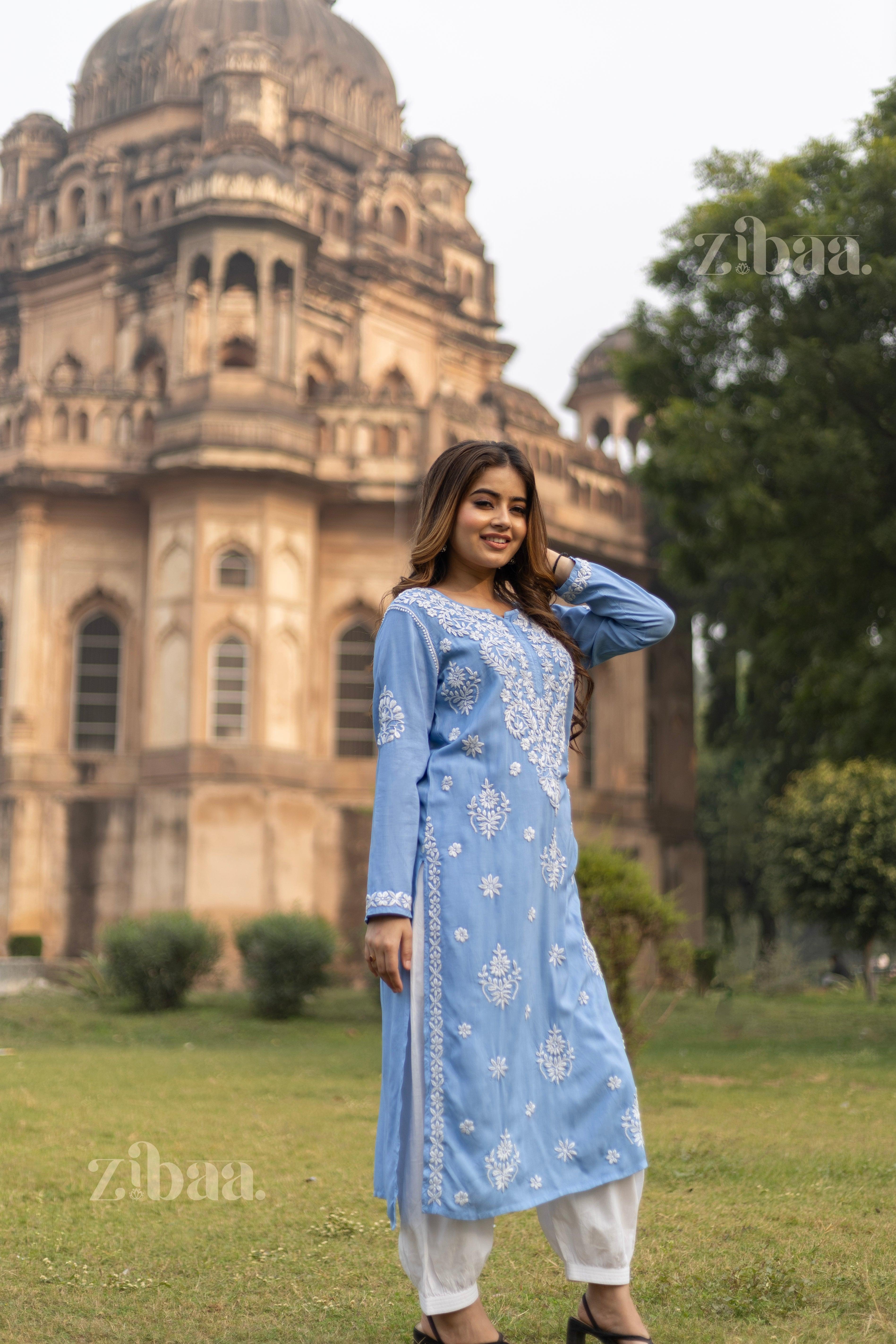 Model wearing a Blue Chikankari Kurta with white embroidery, posing in front of a historic monument in a serene outdoor setting.