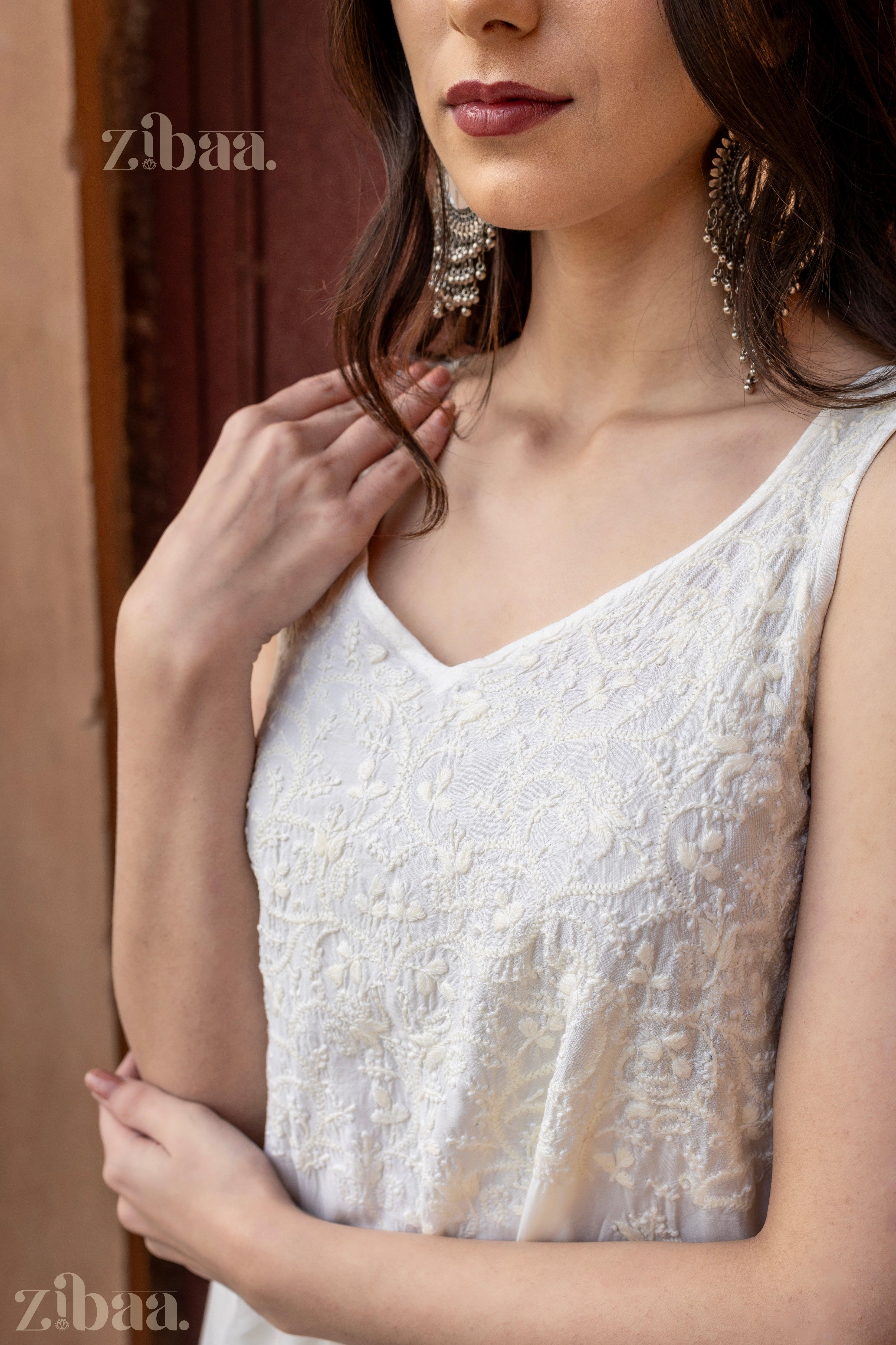 Close-up of a sleeveless Chikankari Kurta Set in white, showing intricate embroidery paired with statement earrings for an elegant look