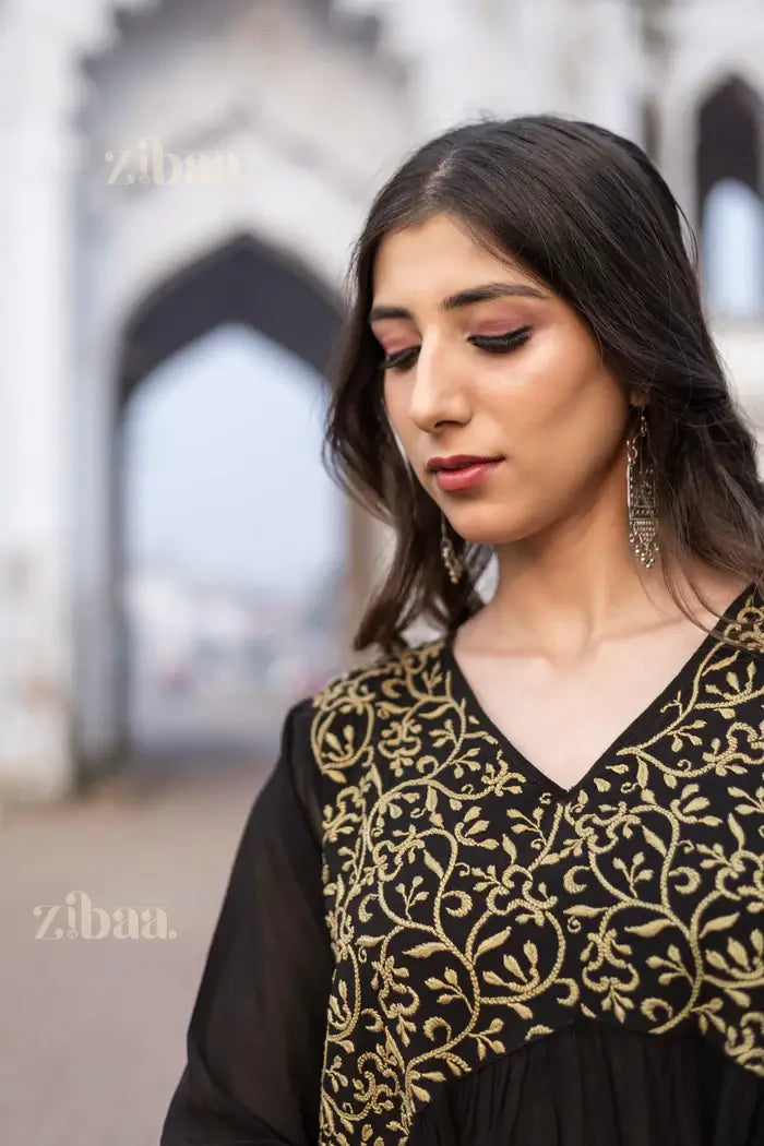 Model wearing a Stunning Black Chikankari Kurti with gold embroidery, showcasing intricate design details against a heritage backdrop