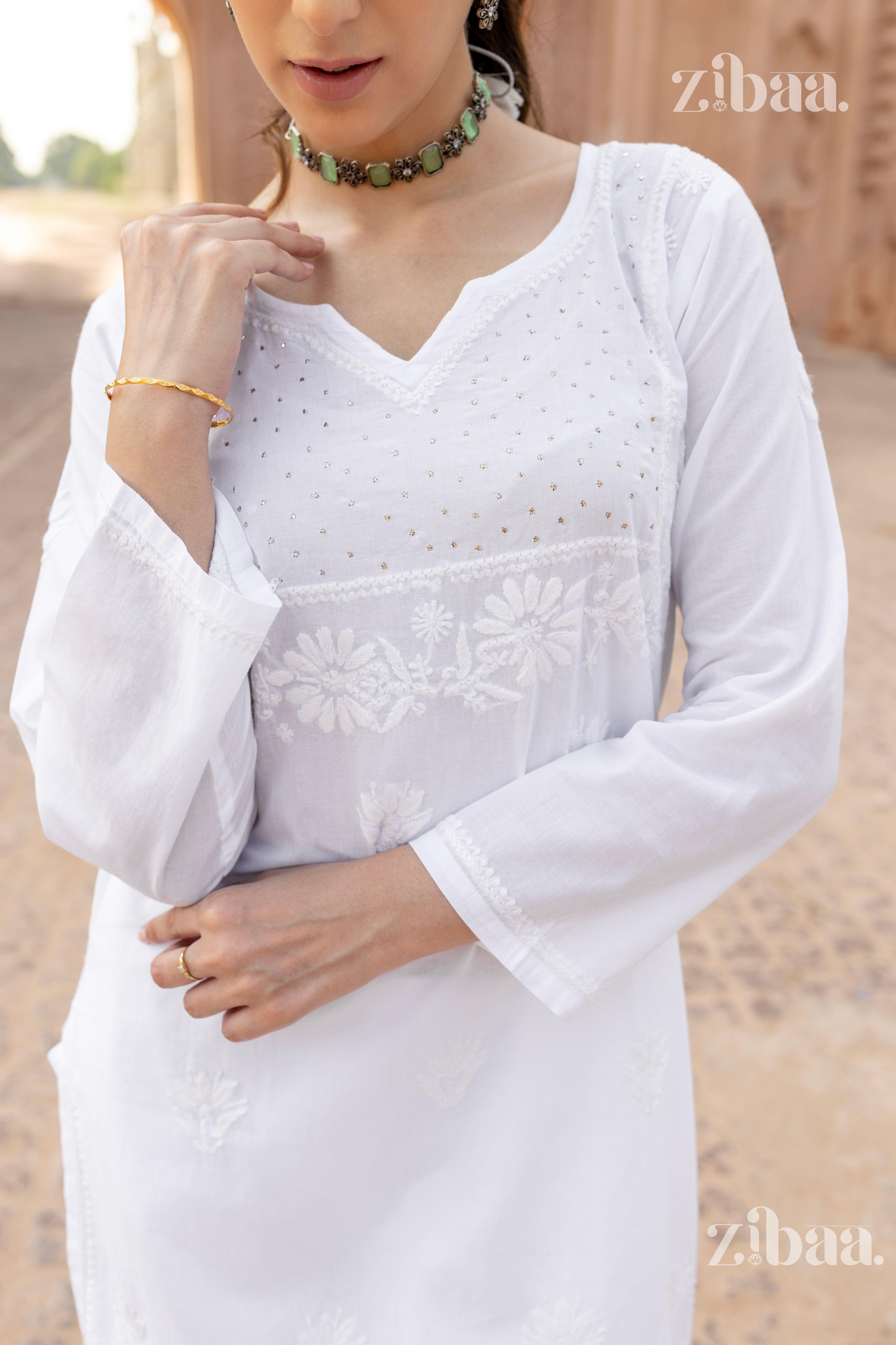 Close-up of a white kurti for women featuring Chikankari embroidery and mirrorwork, styled with a green choker necklace and bracelet.