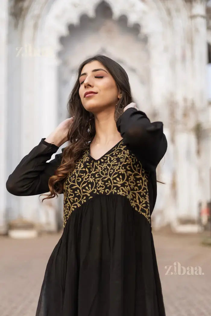 A model wears a Beautiful Black Chikankari Kurti with gold embroidery, depicting traditional elegance in a quiet outdoor setting.