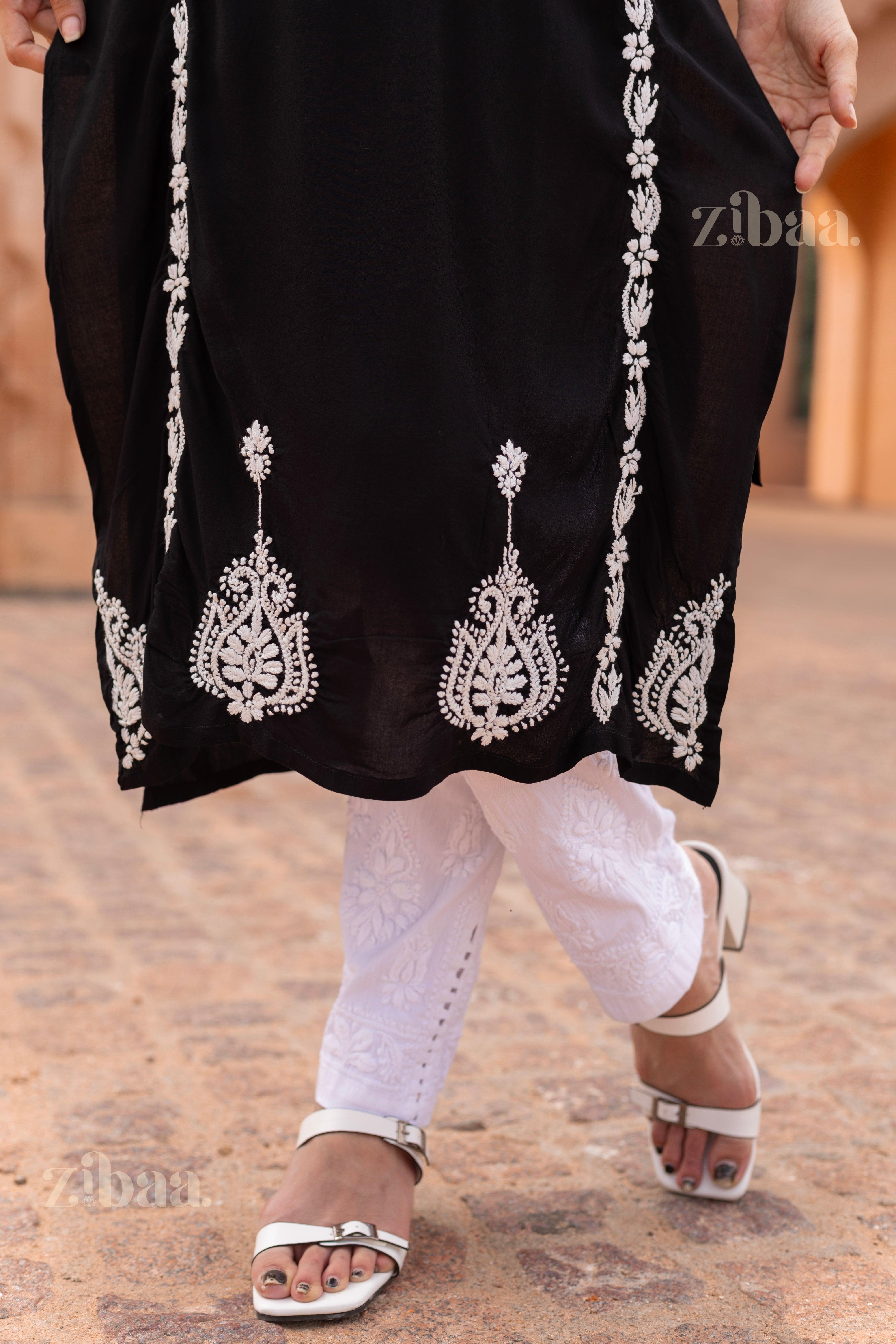 Close-up of a Black Kurti with intricate white embroidery on the hem, paired with white pants and heels, showcasing traditional elegance