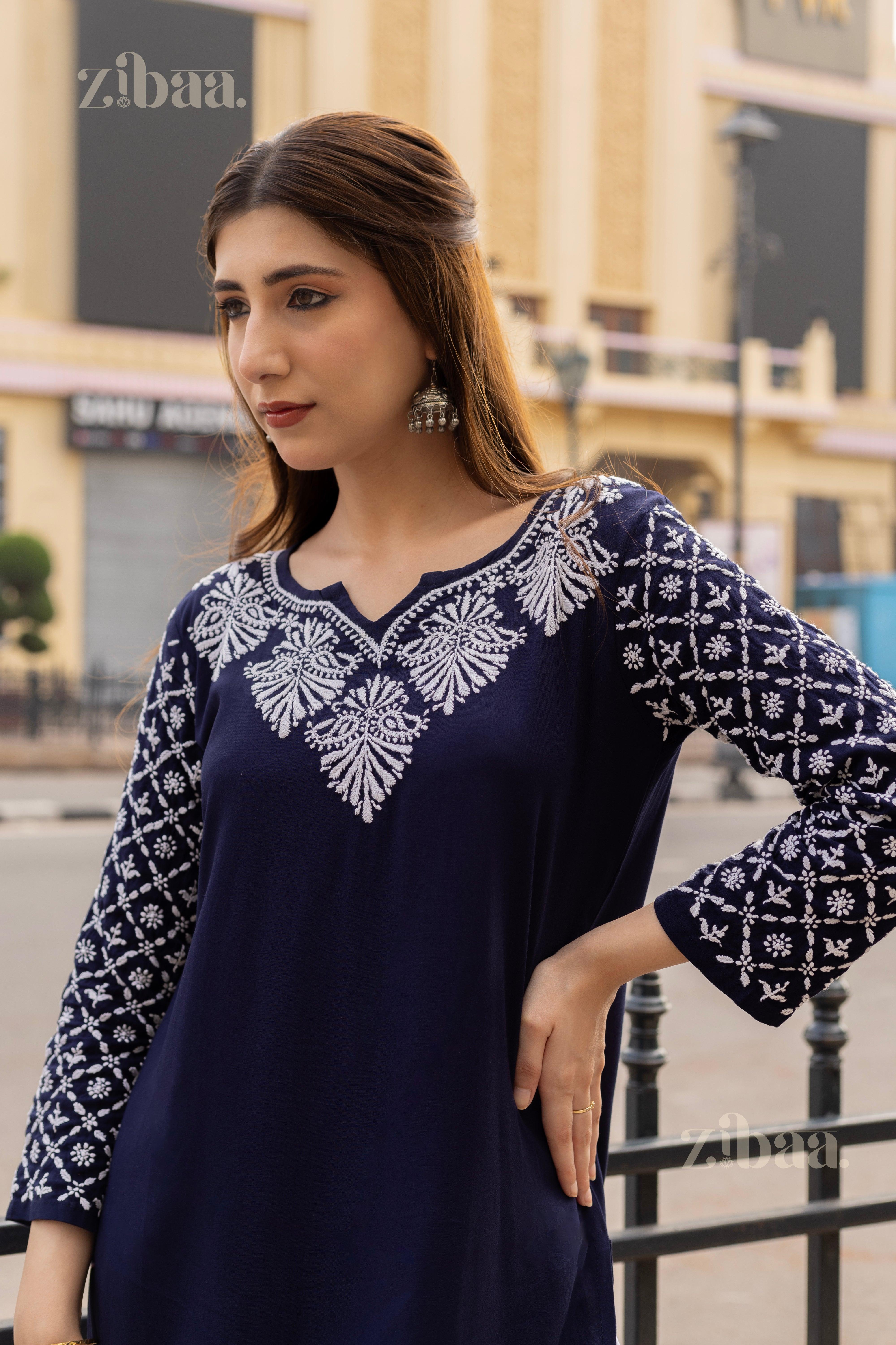 Model wearing a Blue Chikankari Kurti with intricate white embroidery on the neckline and sleeves, posing in a modern outdoor setting