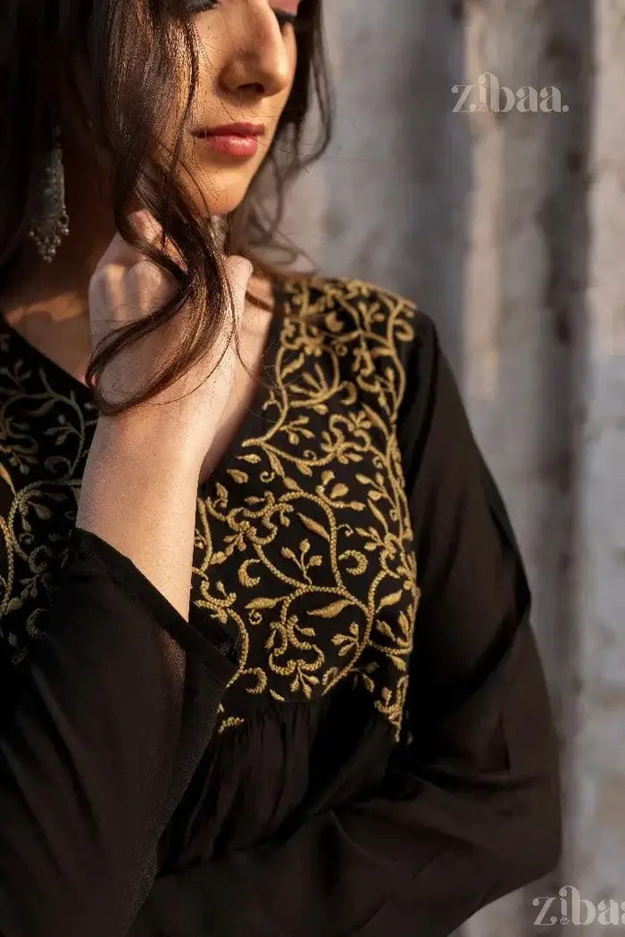 A close-up of a black Chikankari Kurti embellished richly with gold embroidery, capturing elegance in tradition under soft lighting.