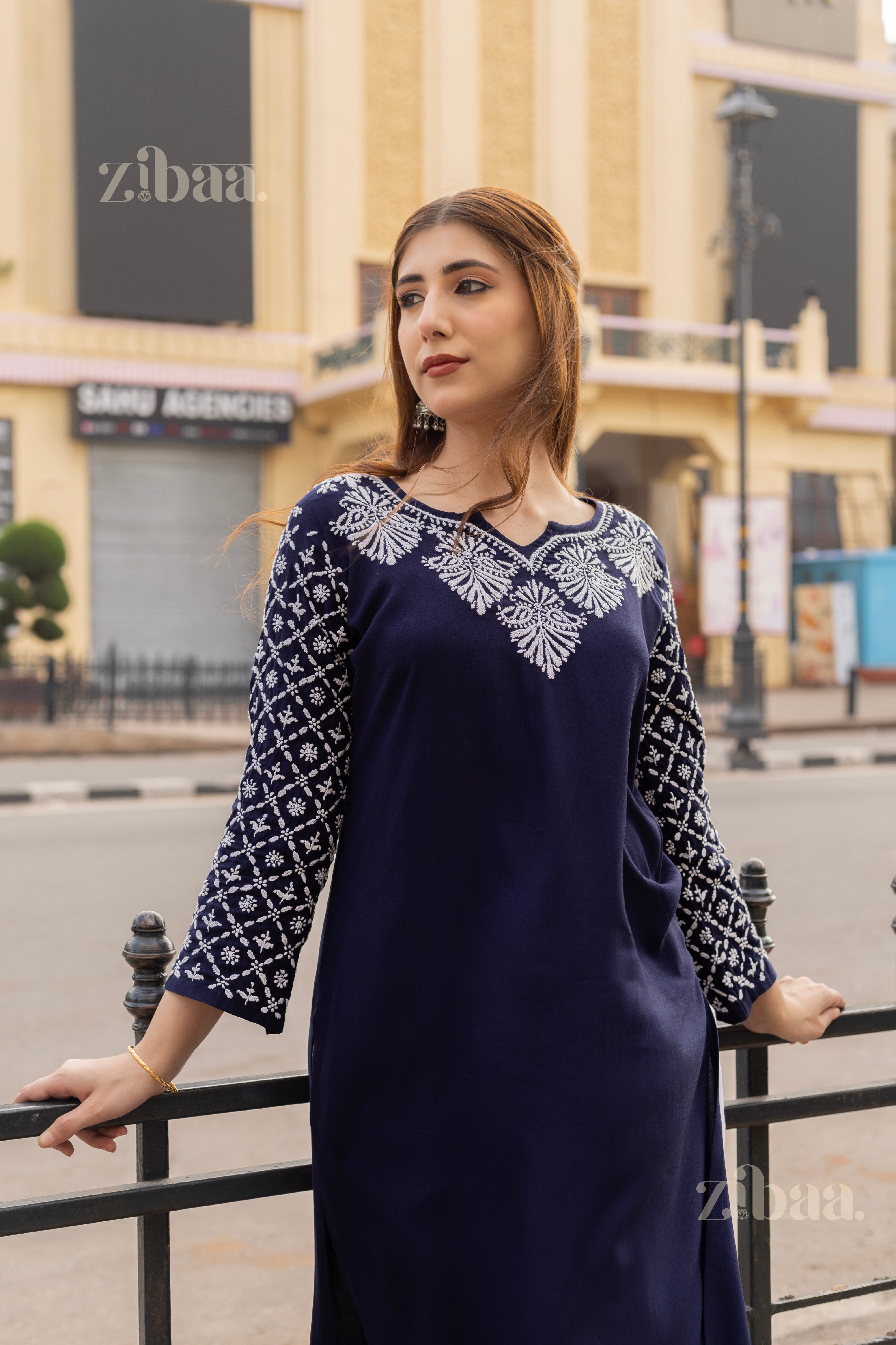 Model wearing a Navy Blue Chikan Kurta with earrings, posing elegantly in front of a historic monument in a serene outdoor setting